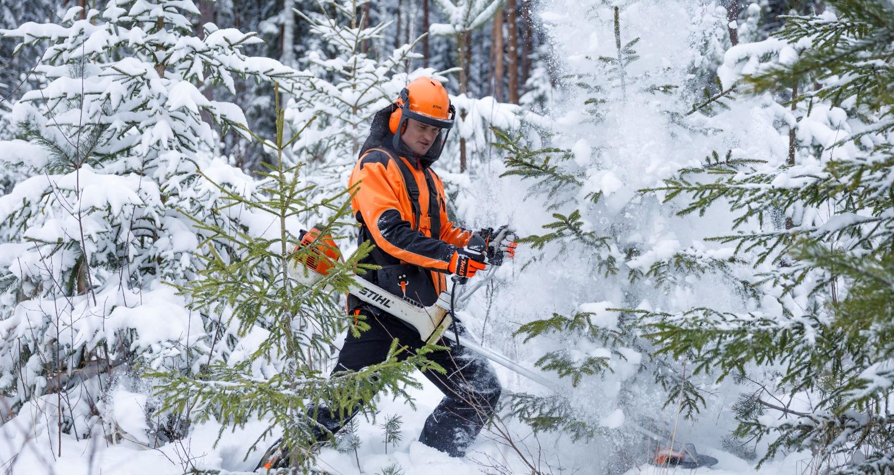 tööriietes mees saega metsas 